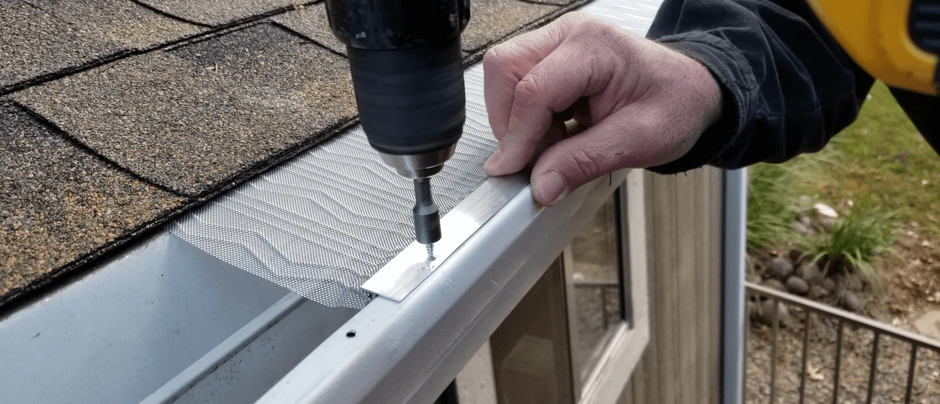 Hand holding mesh gutter guard drill screw gutter lip, Winter Springs